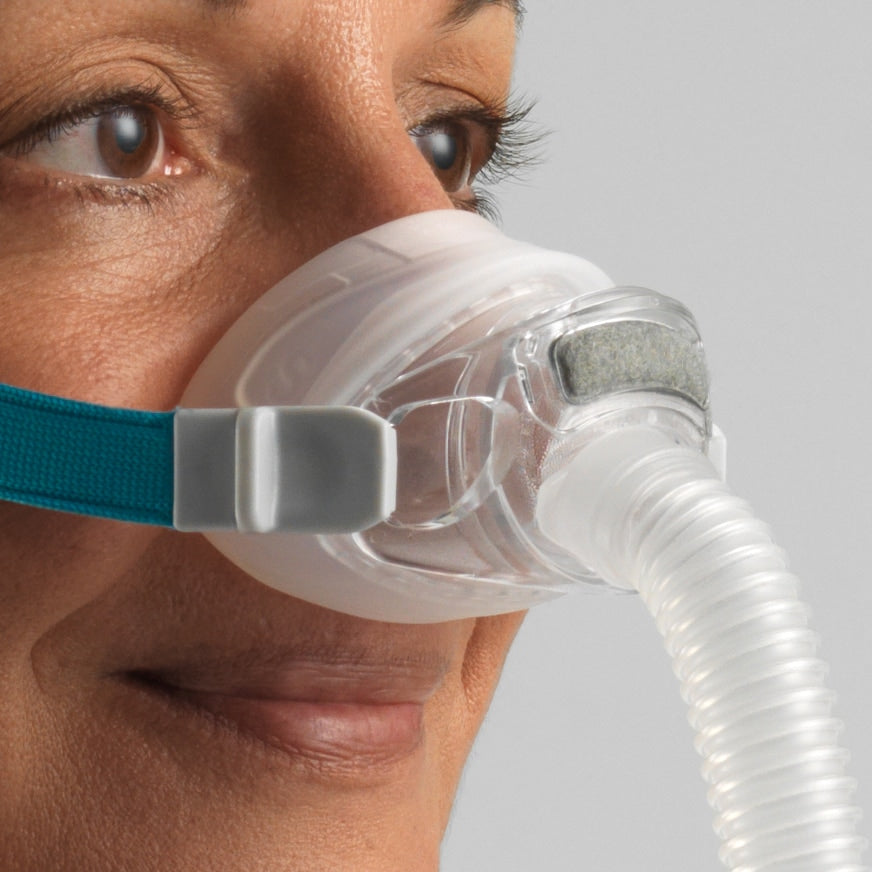 Person wearing a CPAP mask with a clear hose on a neutral background