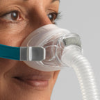Person wearing a CPAP mask with a clear hose on a neutral background
