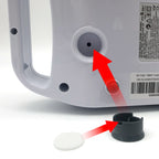 Medical device with a red arrow pointing to a small hole, accompanied by a black cap and white object on a white background.