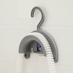 Gray hook with coiled white hose against a light tiled wall