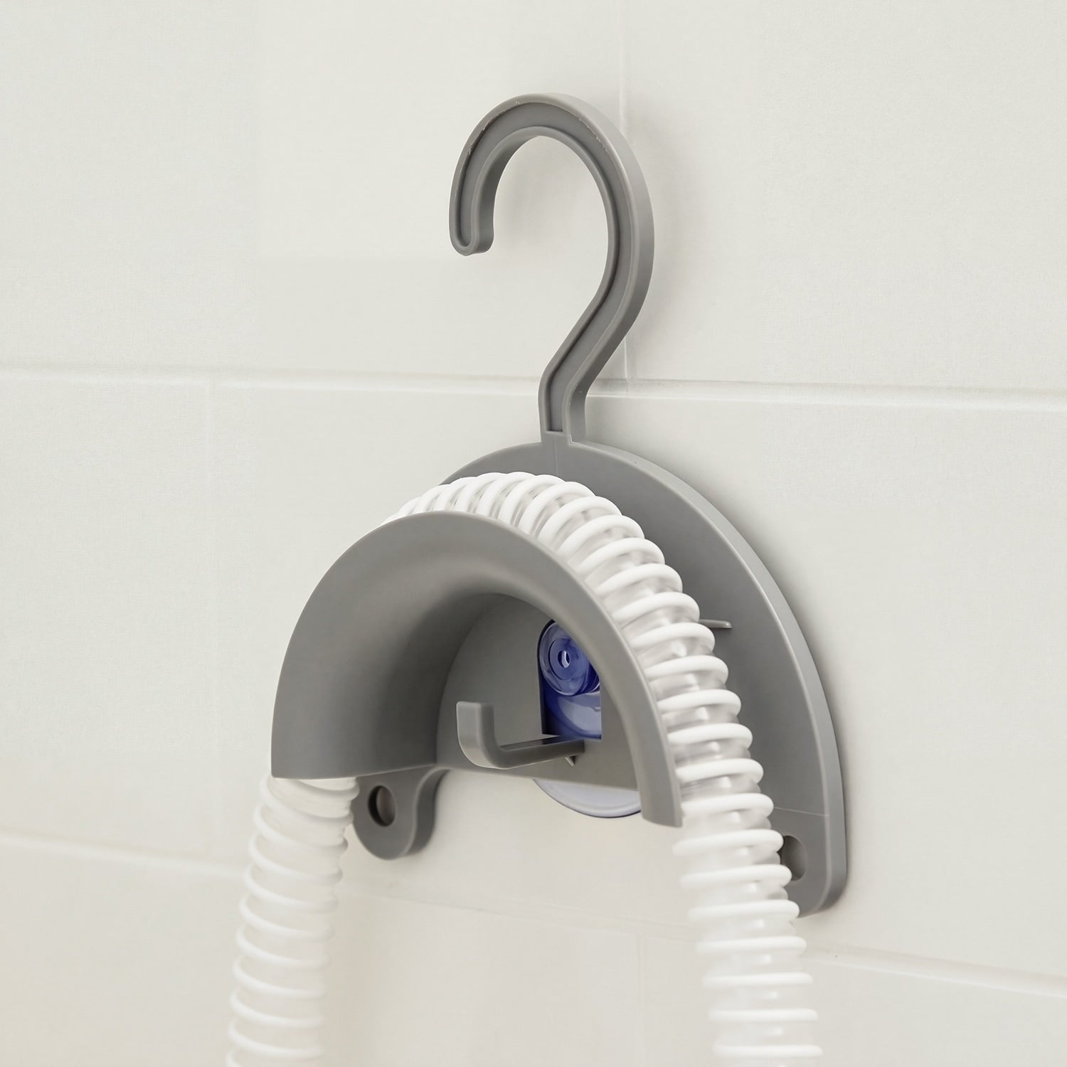 Gray hook with coiled white hose against a light tiled wall