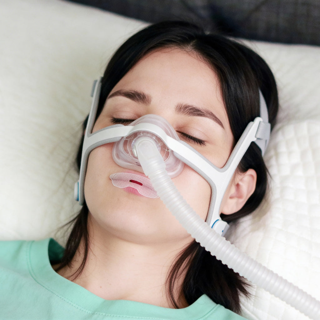 Woman using a CPAP mask to sleep, with coaphero mouth tape  