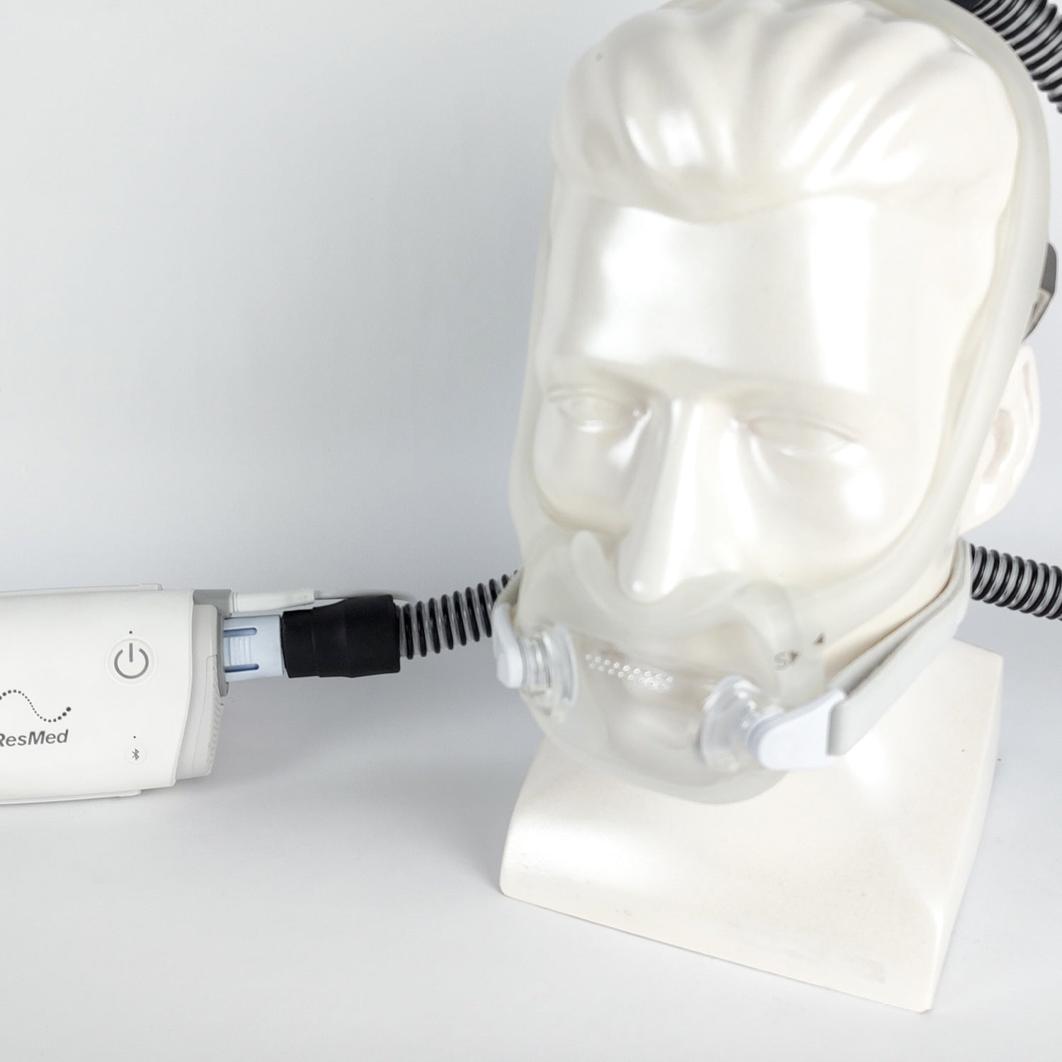 ResMed CPAP device on a mannequin head with a white background