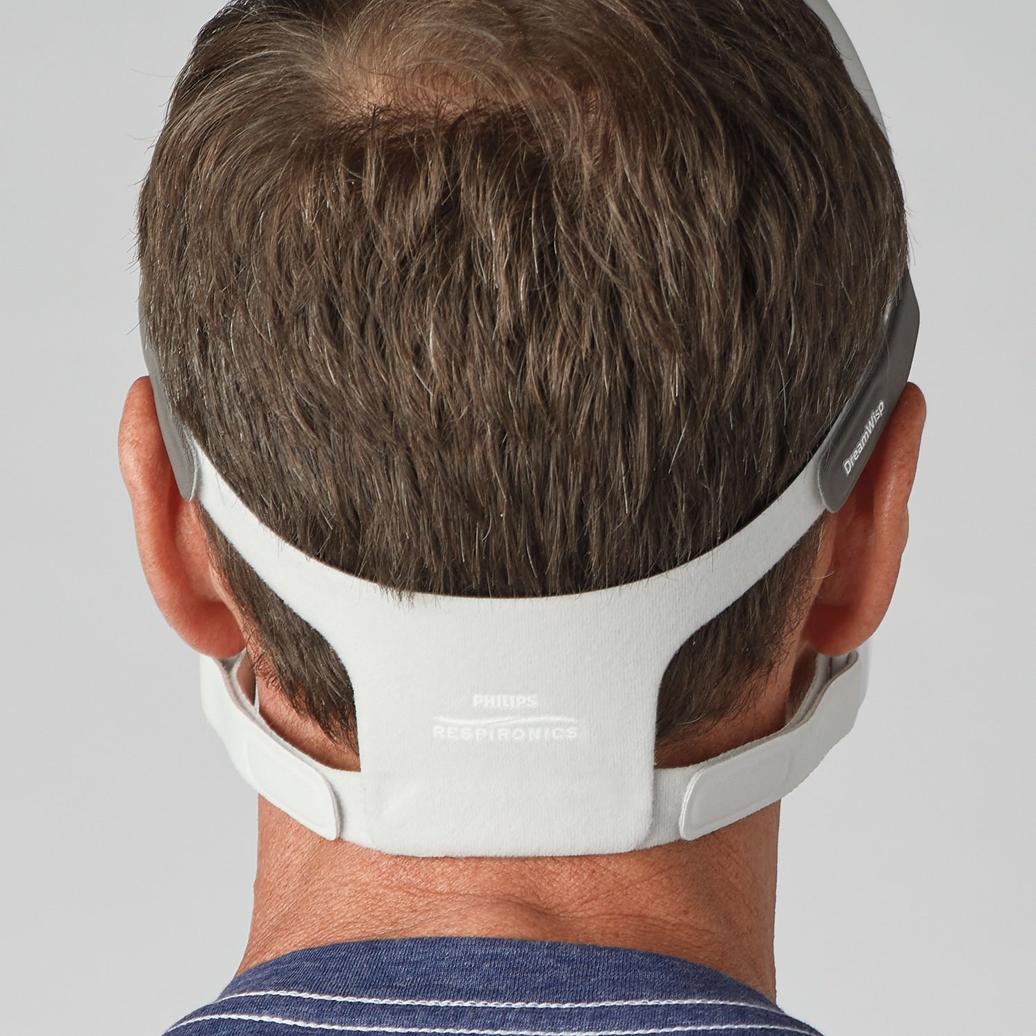 Person wearing a white headgear with a gray strap on a plain background
