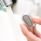 Hand holding a water filter cartridge under running water