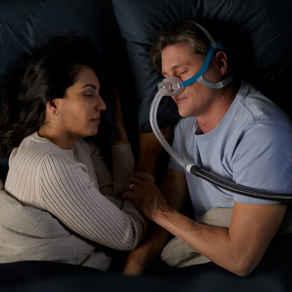 Man in bed sleeping with a Nova CPAP Mask on 