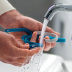 Person washing fisher paykel nova micro under running water from a faucet.