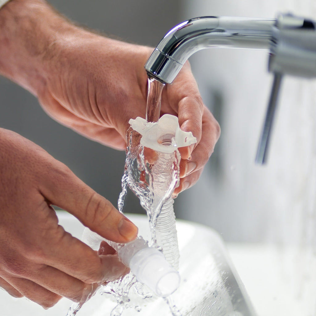Person washing nova micro frame swivel under running water from a faucet.