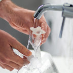Person washing nova micro frame swivel under running water from a faucet.