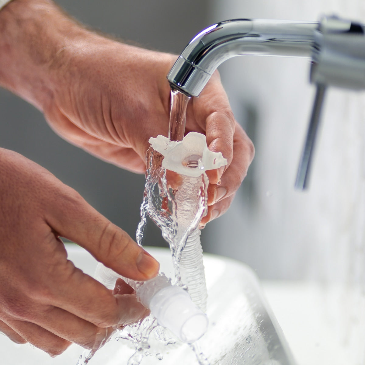 Person washing nova micro frame swivel under running water from a faucet.