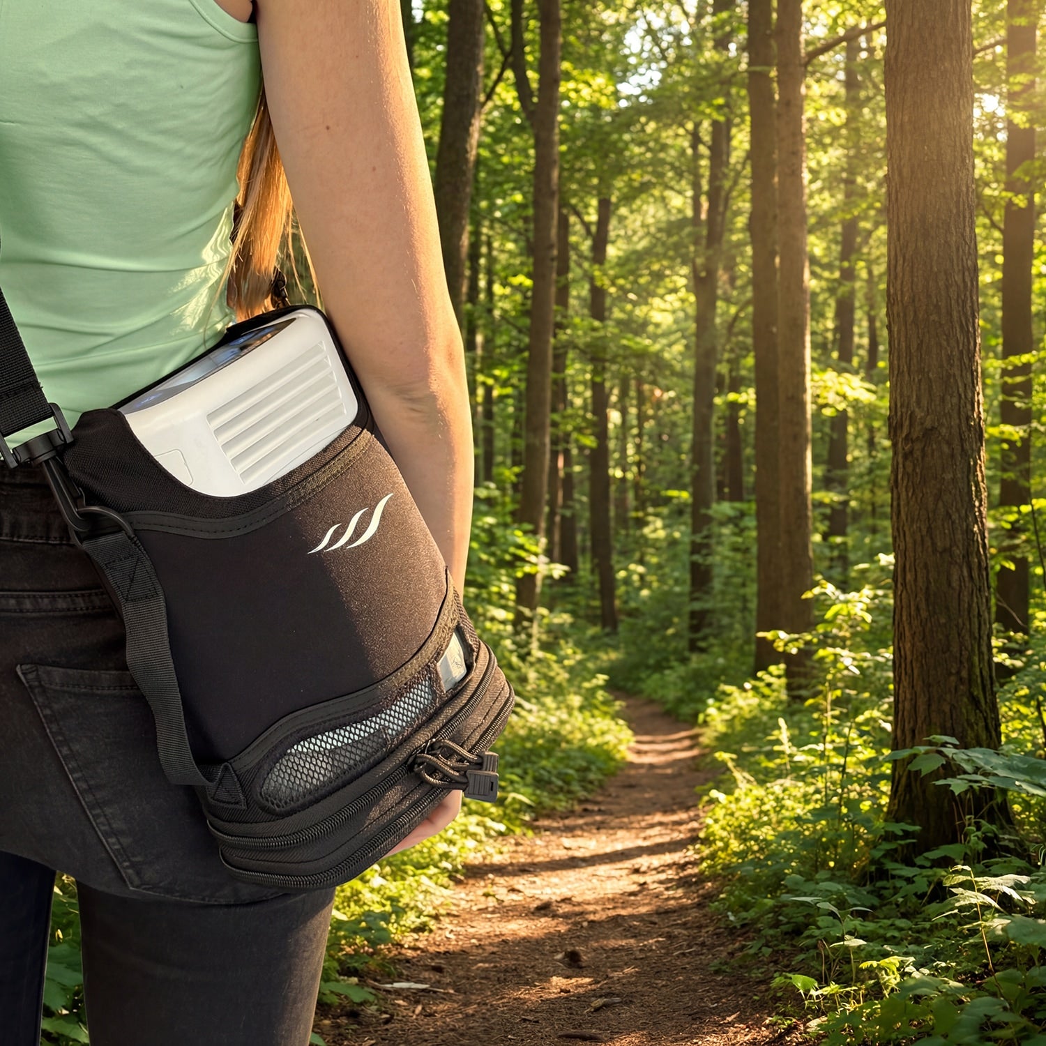Person walking in a forest with a Freestyle portable concentrator bag on their back