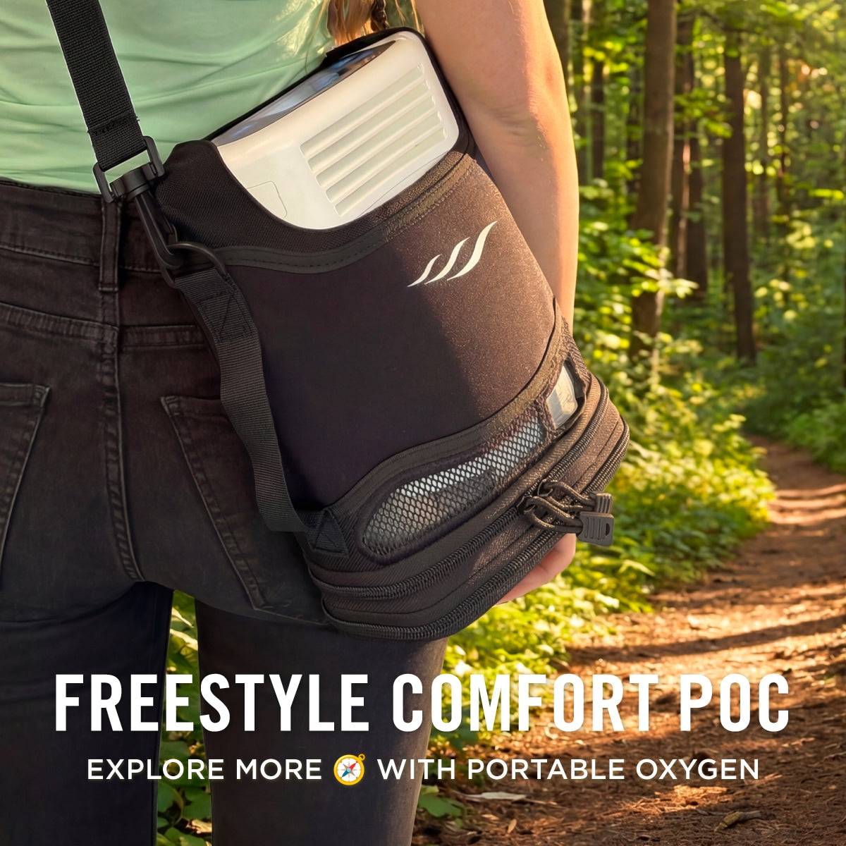 Person holding a portable oxygen tank with 'Freestyle Comfort' branding in a forest setting.