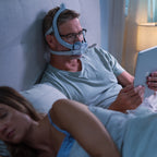 Man wearing Resmed AirTouch F30i COMFORT CPAP Mask while reading on iPad