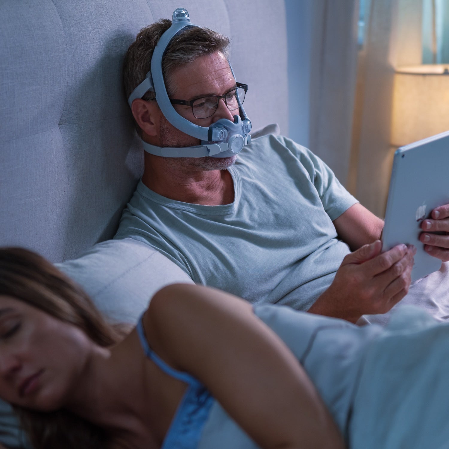 Man wearing Resmed AirTouch F30i COMFORT CPAP Mask while reading on iPad