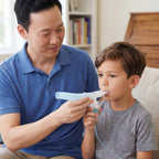Man helping a young boy use a nebulizer at home