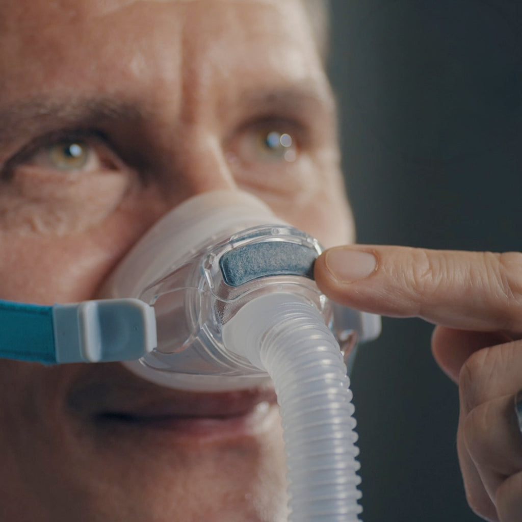 Person using a CPAP mask with a dark background