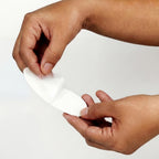 Hands holding a mouth strip against a plain background