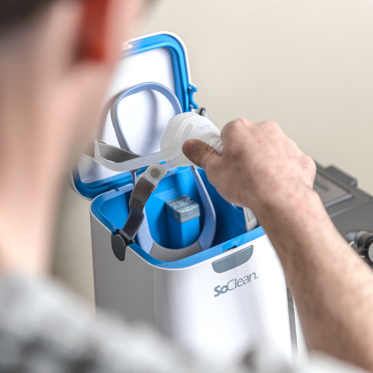 Person interacting with a SoClean device, focusing on the hands and appliance.