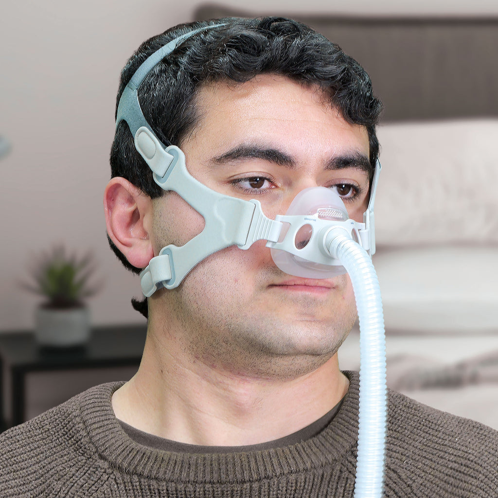 Man wearing a CPAP mask with a hose in a room setting