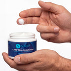 Hand applying Snugell CPAP Skin Moisturizer cream to another hand against a white background