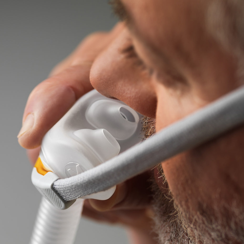 Person holding fisher paykel solo nasal pillow CPAP mask with a blurred background