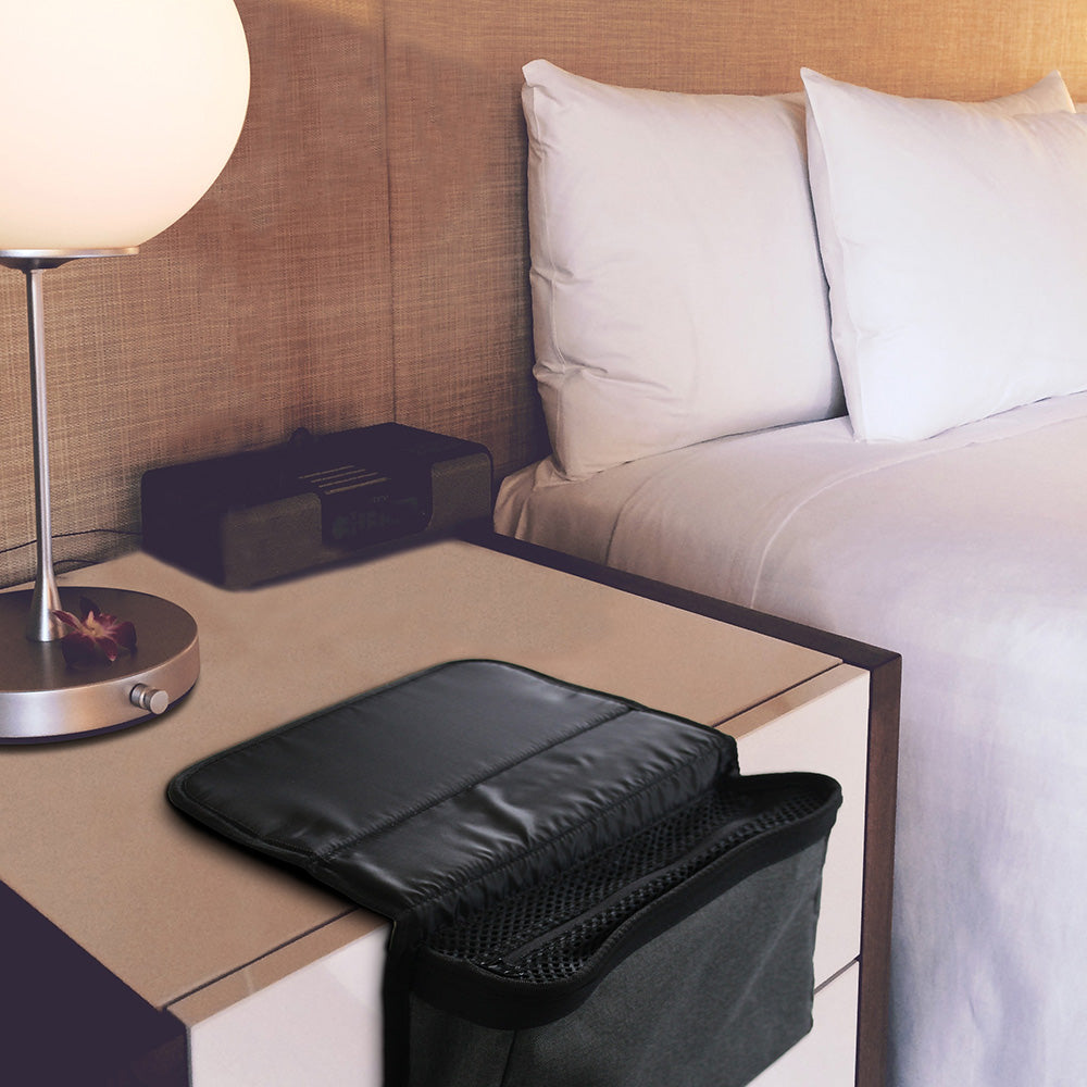 Black Bedside CPAP machine organizer  on a nightstand next to a bed with white pillows.