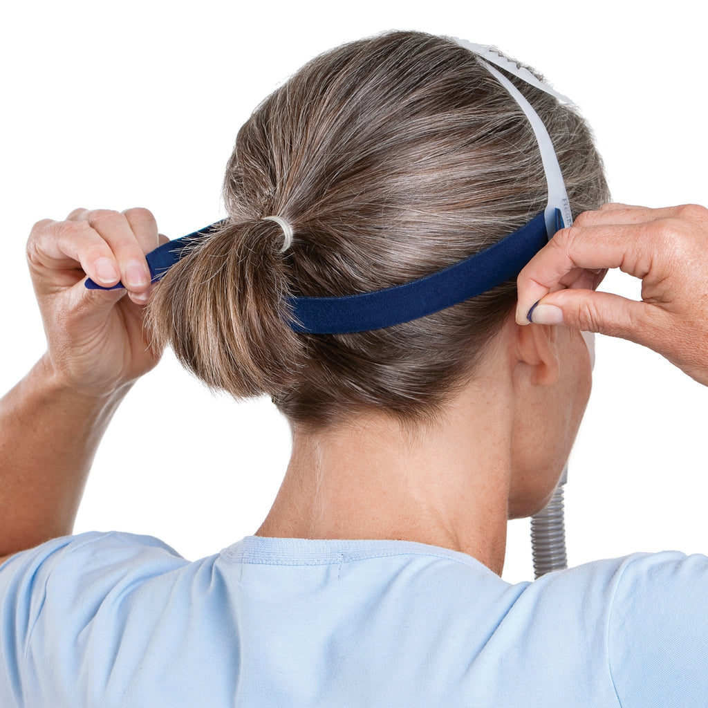 Person adjusting a blue headgear with a white background