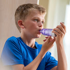 Child using a purple optichamber vhc device with a neutral background