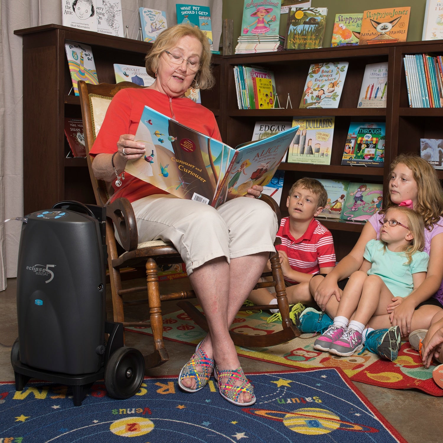 Woman reading a book to children in a library setting with an Eclipse Oxygen Concentrator 