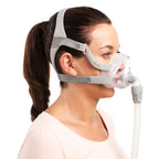 Woman wearing a ResMed CPAP mask on a white background
